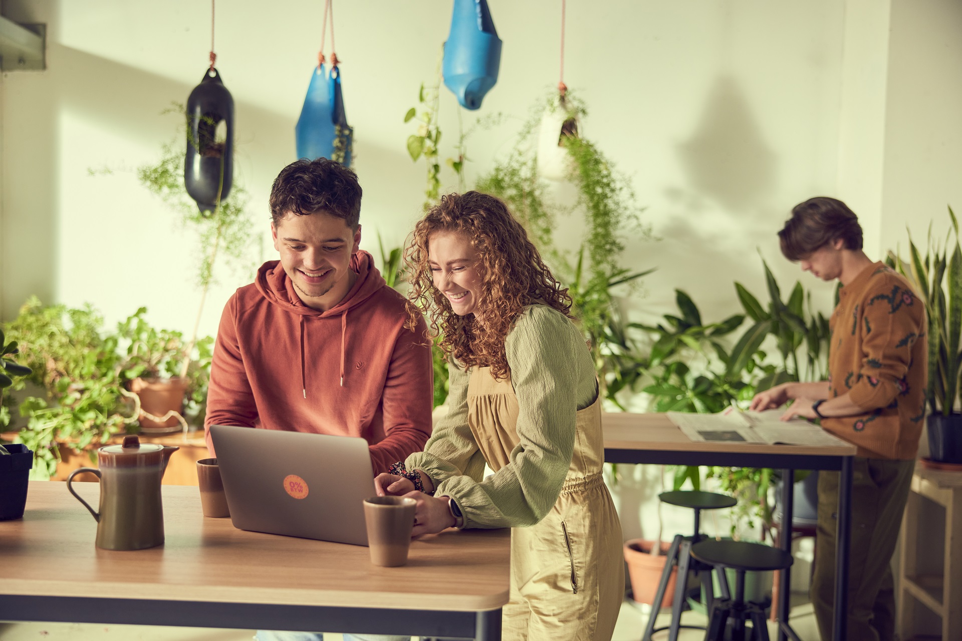 Jongen en meisje werken samen in een lichte en groene omgeving op de laptop.